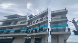 Un immeuble à plusieurs étages doté de balcons, une enseigne indiquant « Ovo » et un auvent bleu.