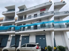 Un edificio de varios pisos con balcones, un coche estacionado adelante y una lona azul cubriendo parte de la estructura.