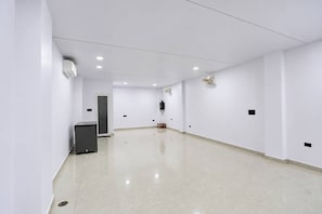 A spacious, well-lit hallway with white walls and a tiled floor, leading to a door at the end. - Hotel O iHeights Luxury Stay & Comfort (Lucknow)