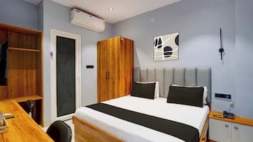 Habitación de hotel con cama, escritorio, armario y aire acondicionado instalado en la pared.