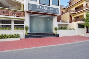 A modern hotel entrance with a glass facade, a sign reading 'iHeights Luxury Stay & Comfort,' and a red-tiled entrance area. - Hotel O iHeights Luxury Stay & Comfort (Lucknow)