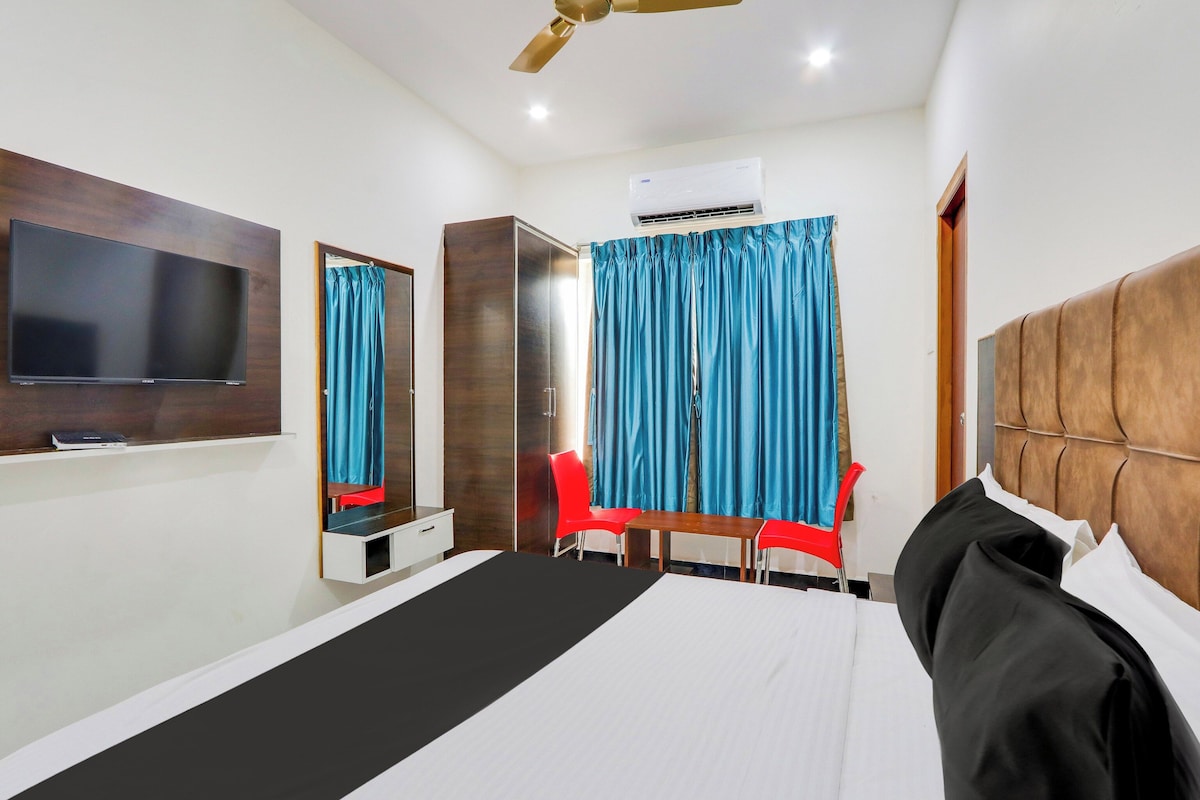 A hotel room with a bed, a TV, a wardrobe, a desk, a chair, and a ceiling fan.