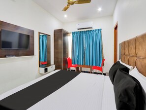 A hotel room with a bed, a TV, a wardrobe, a desk, a chair, and a ceiling fan. - Hotel O Arjun Residency (Khammam)