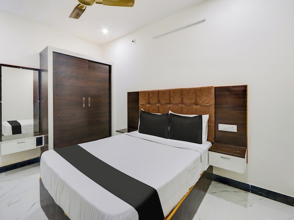 A modern bedroom with a large bed, a wardrobe, and a mirror.
