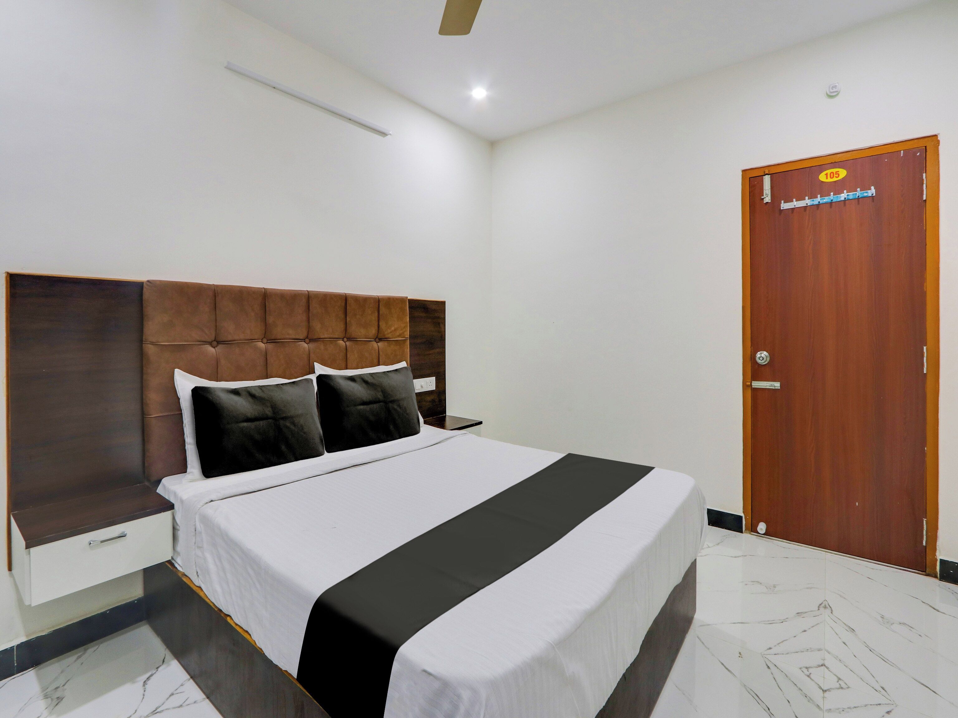 A hotel room with a bed, a wooden door, and a white wall.