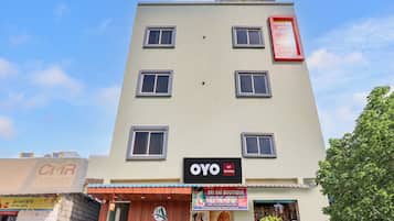 Un edificio de varios pisos con letreros que indican Hotel Arjun Residency, OYO y Sri Sai Boutique.