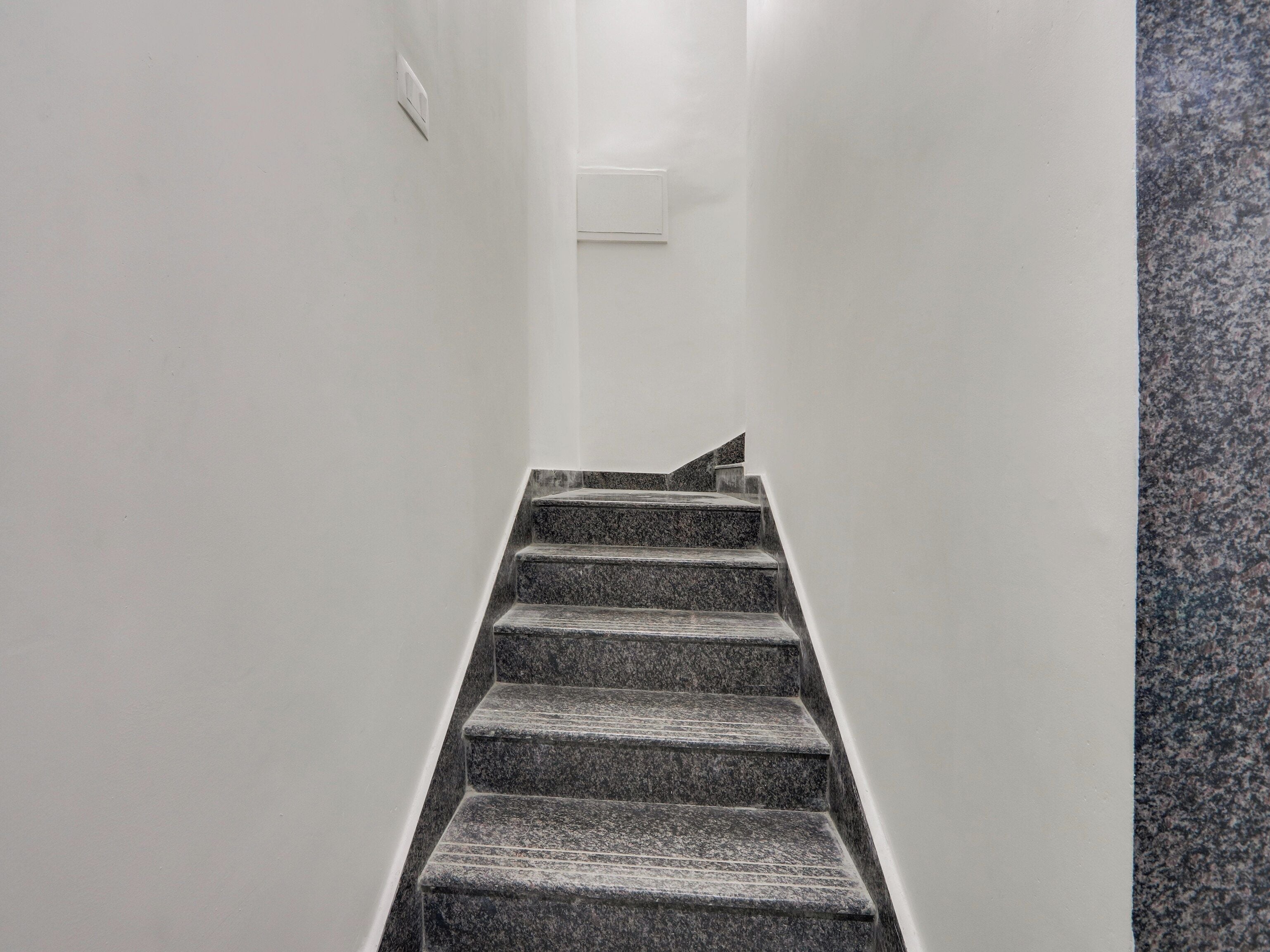 A staircase with a handrail and carpeted steps leading to a landing.