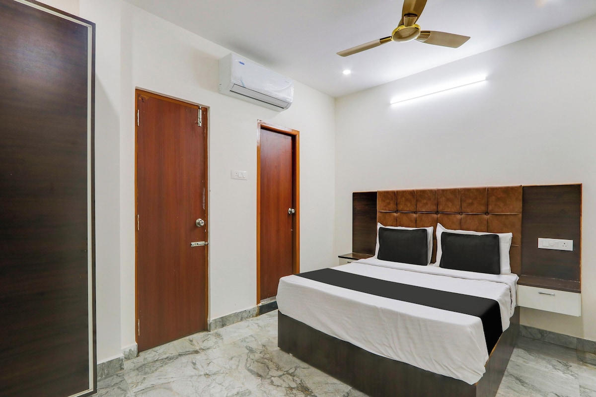 A hotel room with a bed, a ceiling fan, an air conditioning unit, and marble flooring.
