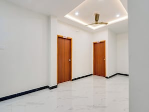 A hallway with two wooden doors, a ceiling fan, and a tiled floor.