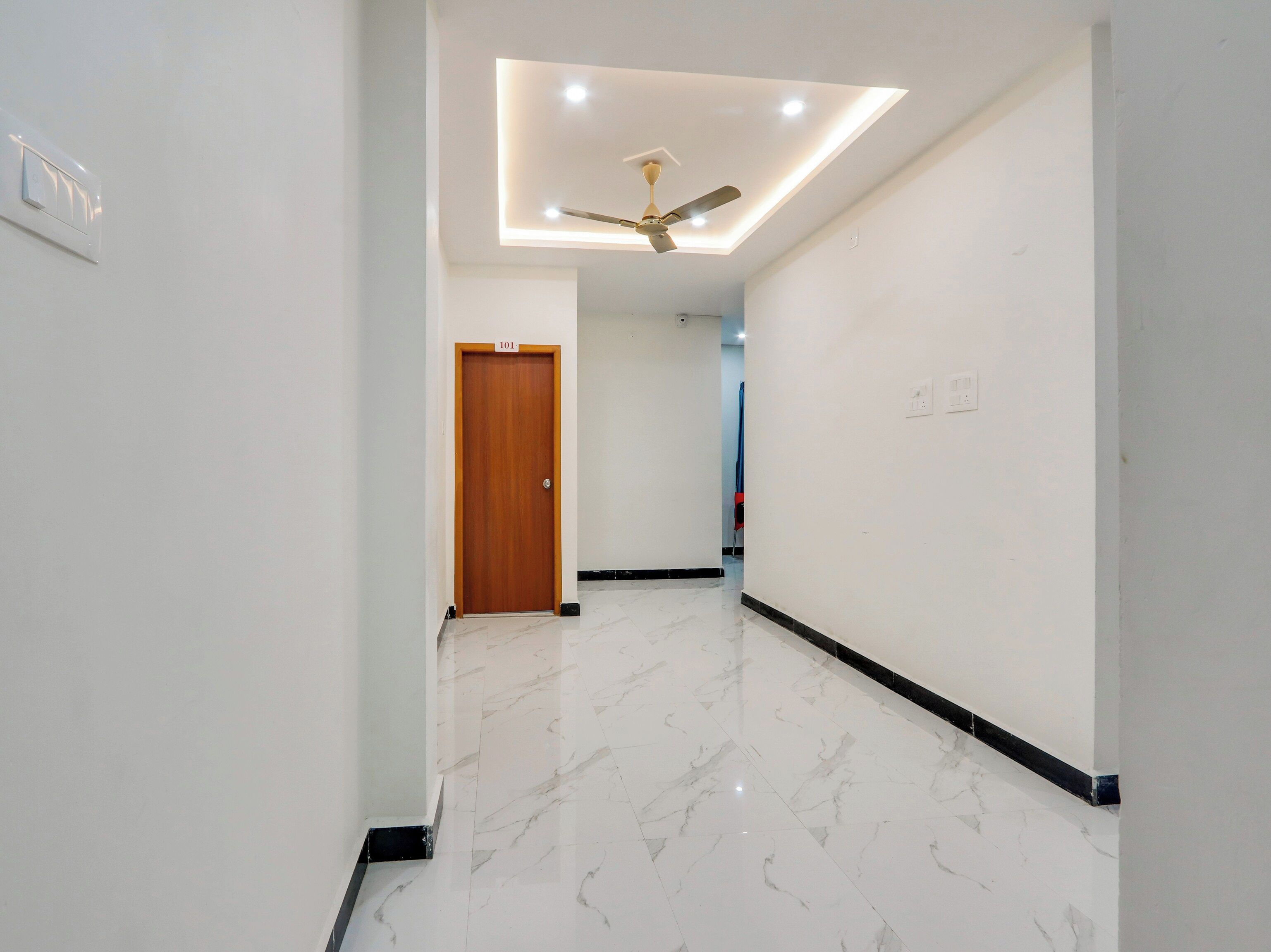 A hallway with a wooden door, a ceiling fan, and a recessed light fixture.