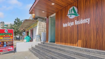 A hotel entrance with a wooden facade and a sign for Hotel Arjun Residency.