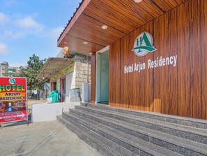 A hotel entrance with a wooden facade and a sign for Hotel Arjun Residency.