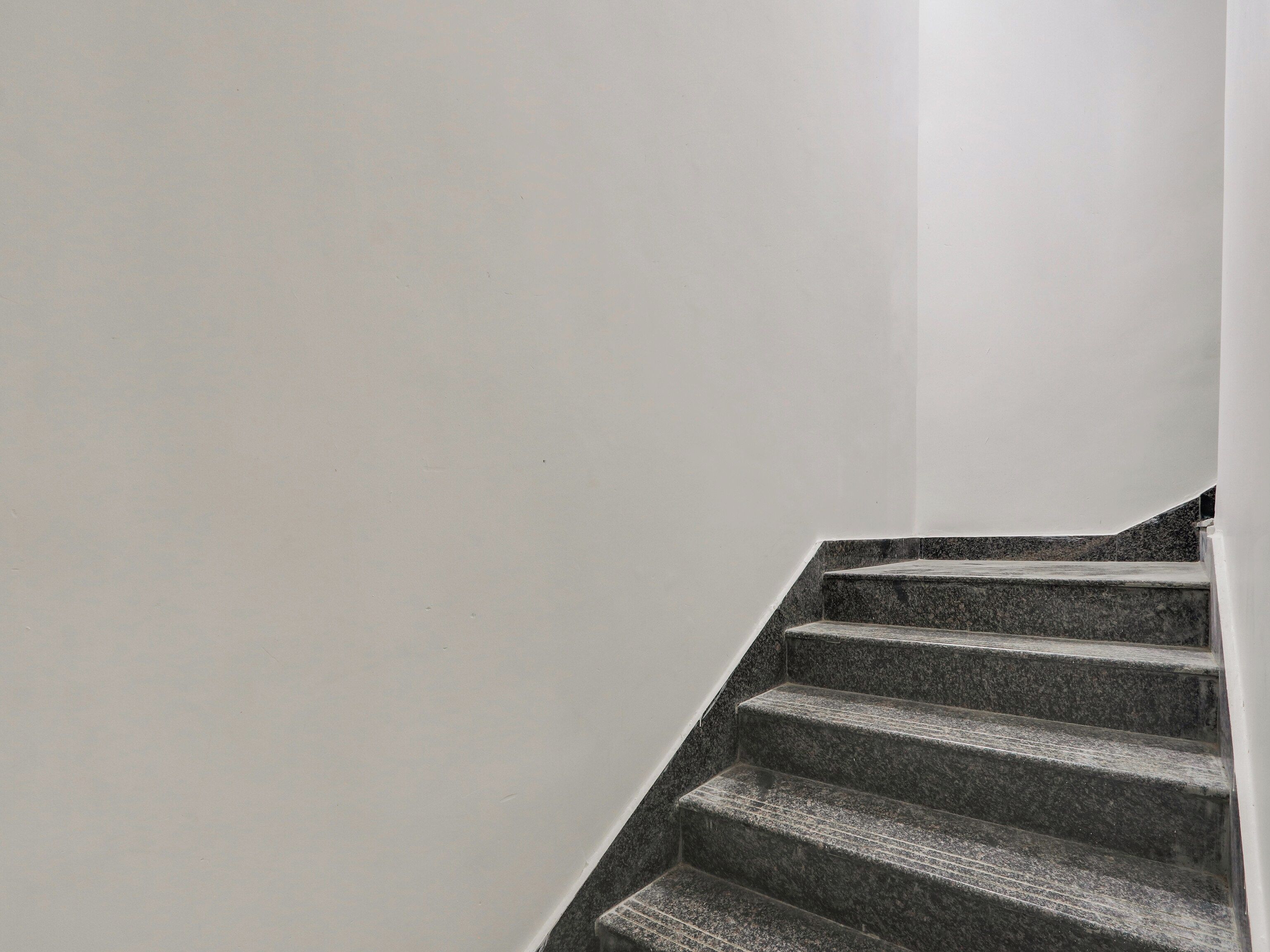 Una escalera con barandilla y pared blanca.
