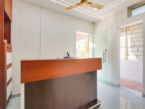 A reception desk with a wooden finish, a ceiling fan, and a glass door leading to an outdoor area.