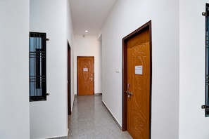 Un pasillo con dos puertas de madera, una con un ventanal y la otra con un cartel.