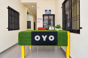 Un área de recepción con una mesa de césped artificial verde, un letrero que dice 'OYO' y una pequeña planta en maceta.