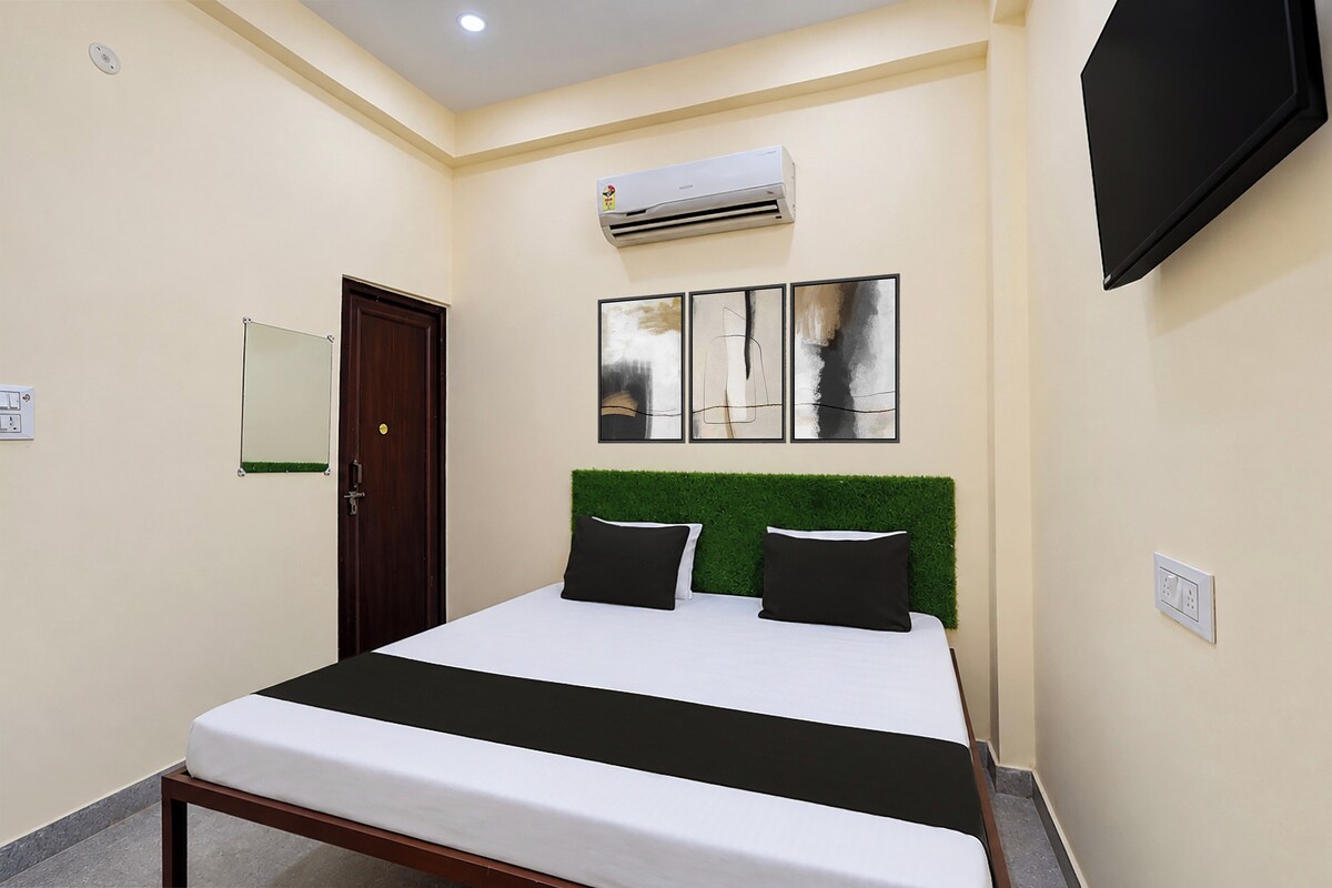 Habitación de hotel con cama, puerta, unidad de aire acondicionado, televisor de pared y toma de corriente.
