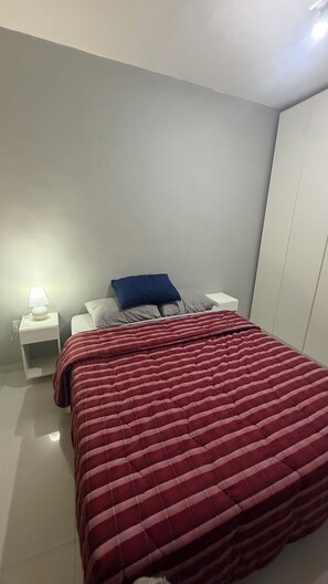 Une chambre à coucher avec un lit, une table de chevet, une lampe et une armoire.
