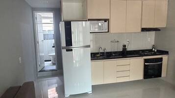 Een moderne keuken met een koelkast, magnetron, fornuis en spoelbak.