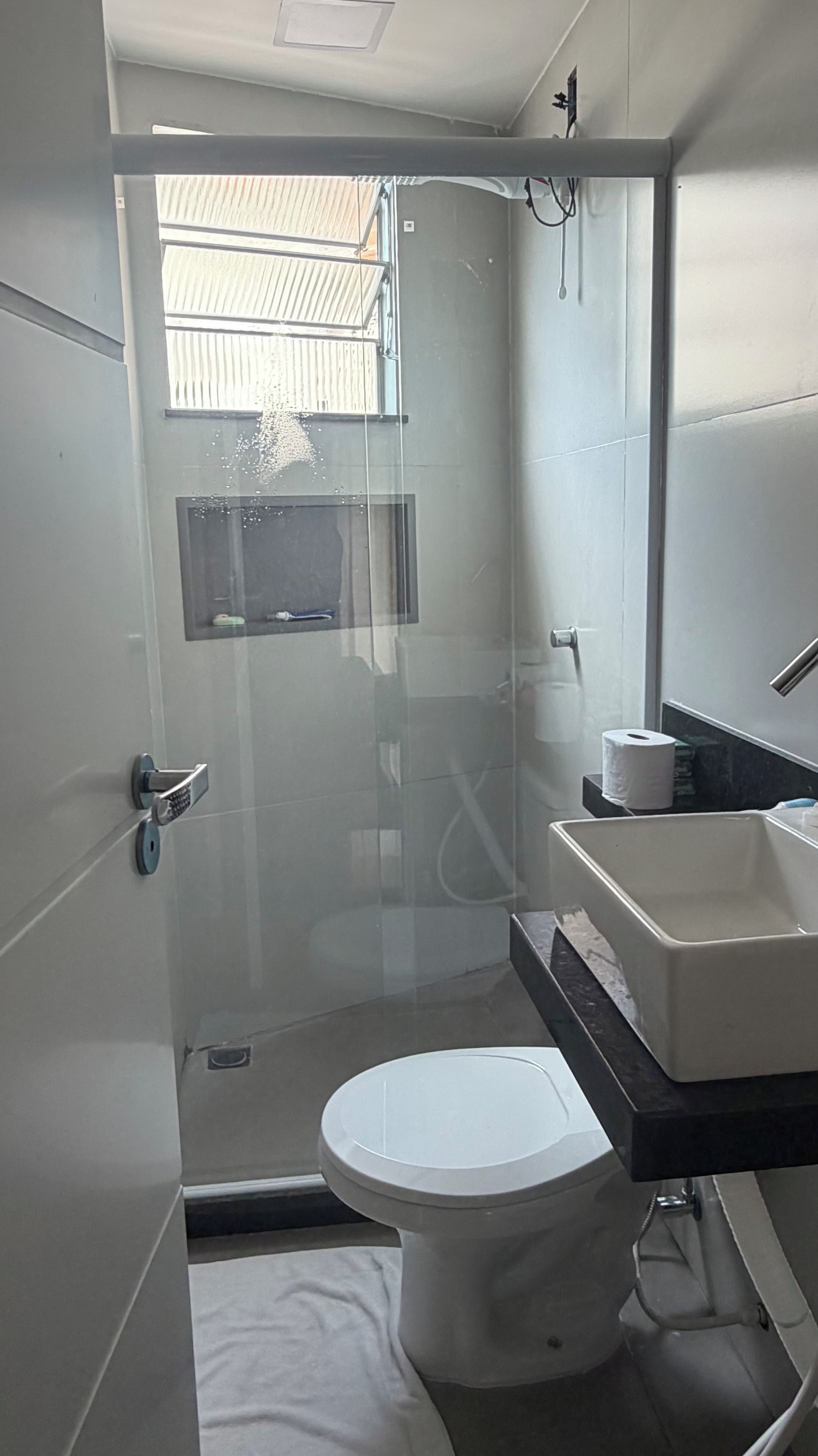 Une salle de bain compacte comprenant des toilettes, une douche à parois de verre et un lavabo avec un miroir.