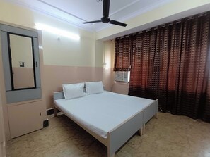 Un dormitorio con cama, armario, ventilador de techo y cortinas estampadas.
