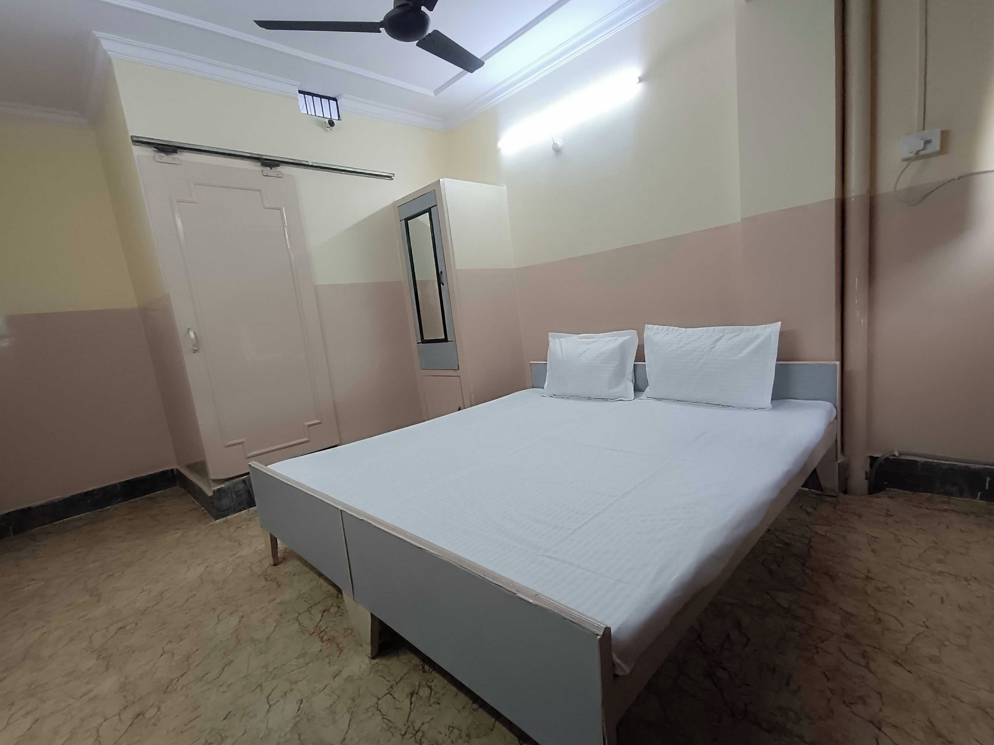 Habitació d'hotel estàndard amb un llit, un armari, un ventilador de sostre i una làmpada.