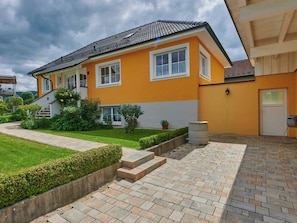 Ein zweigeschossiges Wohnhaus mit Ziegeldach, einem gepflegten Rasen und einer gepflasterten Auffahrt zum Eingang.