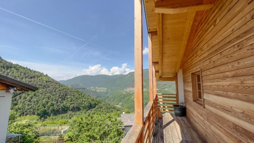 Une cabane en bois dotée d’un balcon donnant sur un paysage montagneux.