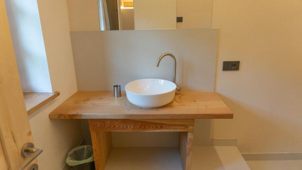 A bathroom with a wooden vanity, a white sink, and a mirror above it.