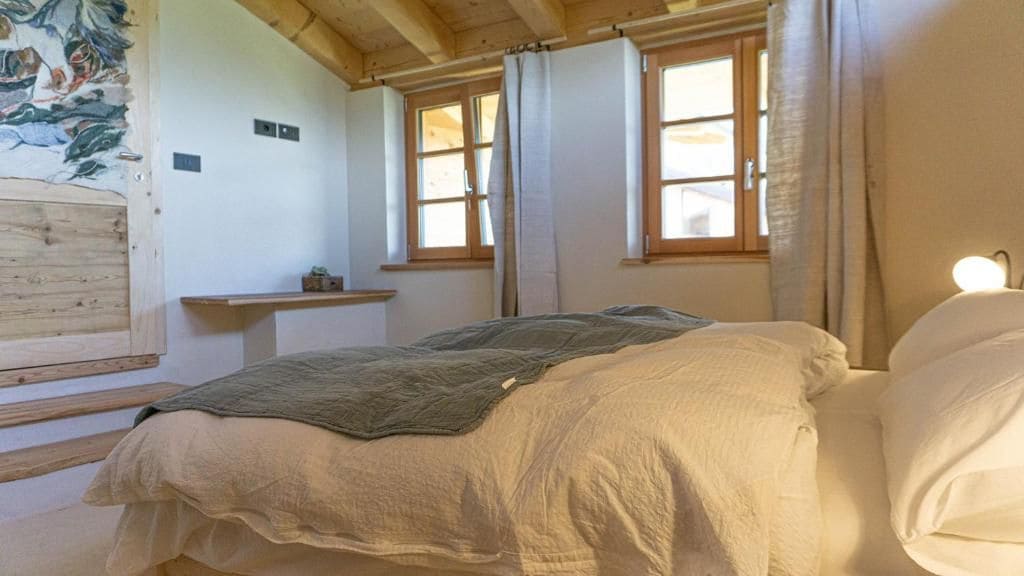 Un dormitori amb un llit, un panell de capçal de fusta, una finestra i una estantanya penjada a la paret.