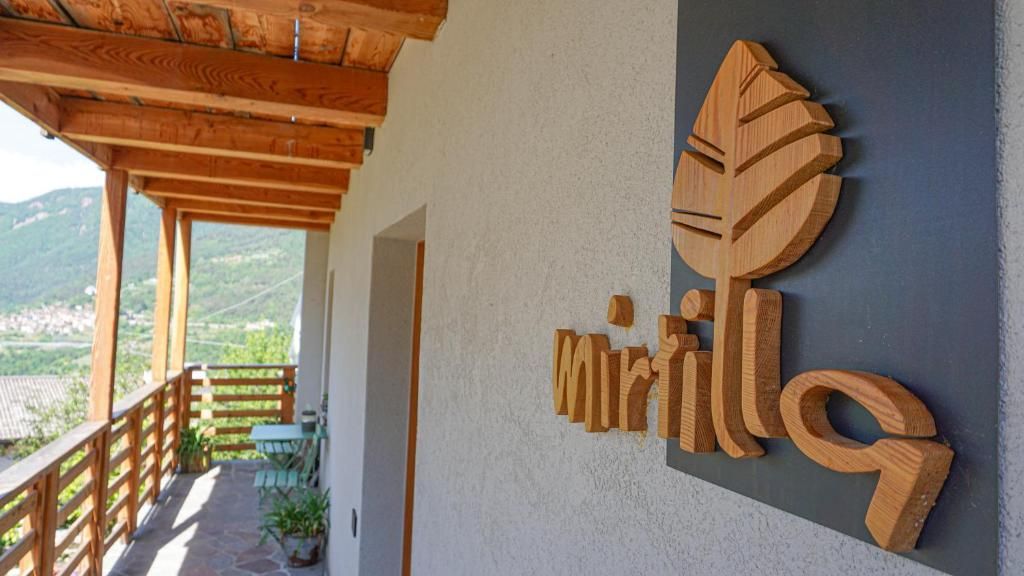 Une enseigne en bois portant le nom « Mirilla » est fixée à la façade d’un immeuble.