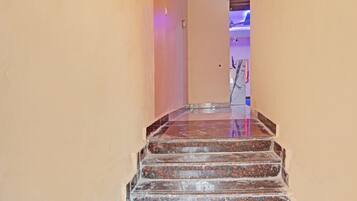 A staircase with a polished stone finish leading to a room with a purple-lit ceiling.