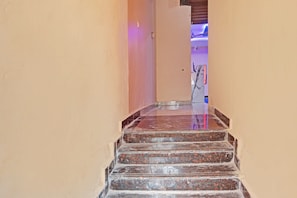 A staircase with a polished stone finish leading to a room with a purple-lit ceiling. - HOTEL O SAI LEELA RESIDENCY (Karimnagar)