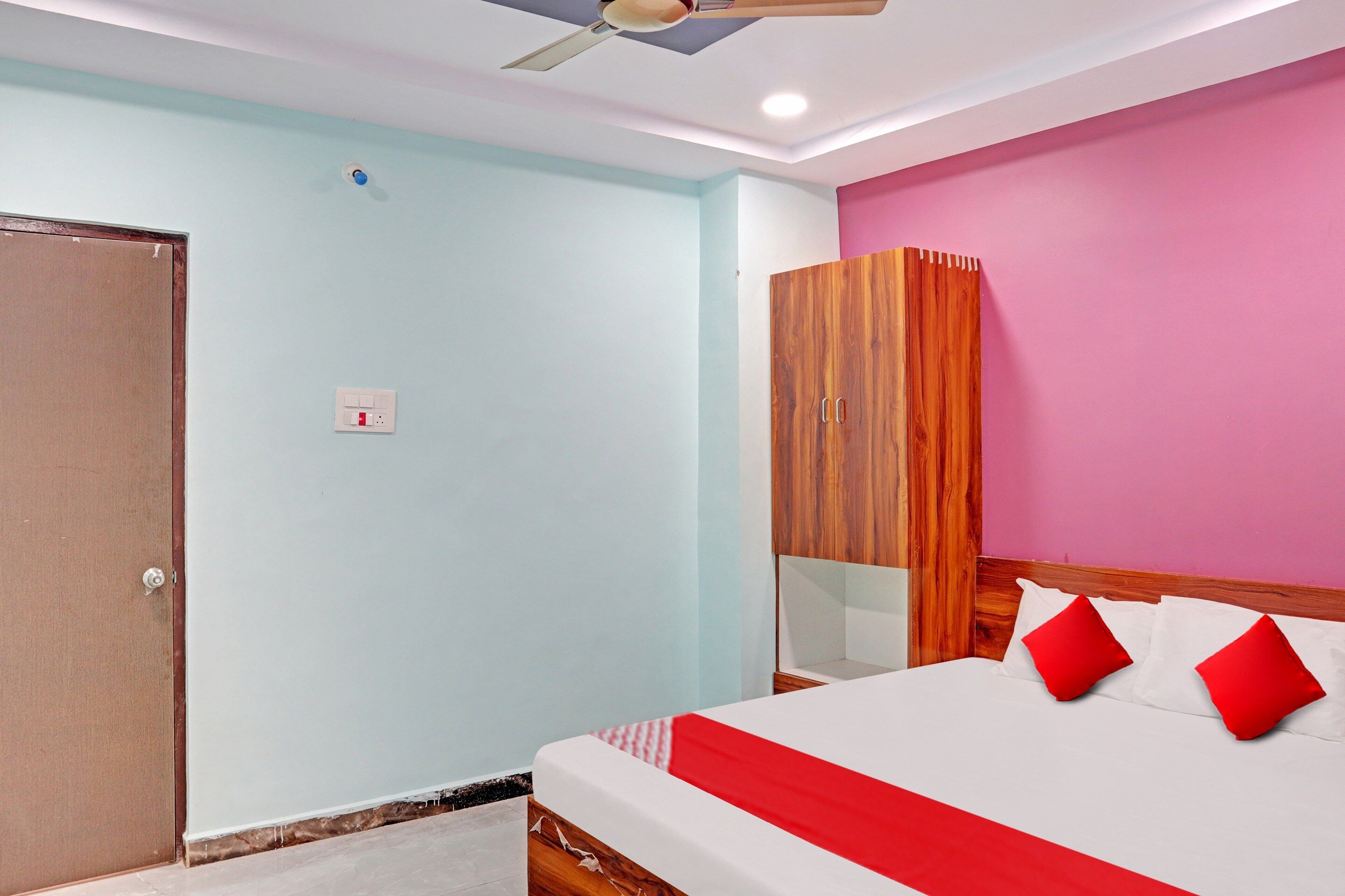 A bedroom with a bed, a wardrobe, a ceiling fan, and a light switch.