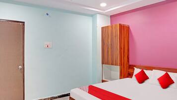 A bedroom with a bed, a wardrobe, a ceiling fan, and a light switch.