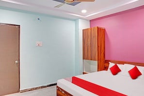 A bedroom with a bed, a wardrobe, a ceiling fan, and a light switch. - HOTEL O SAI LEELA RESIDENCY (Karimnagar)