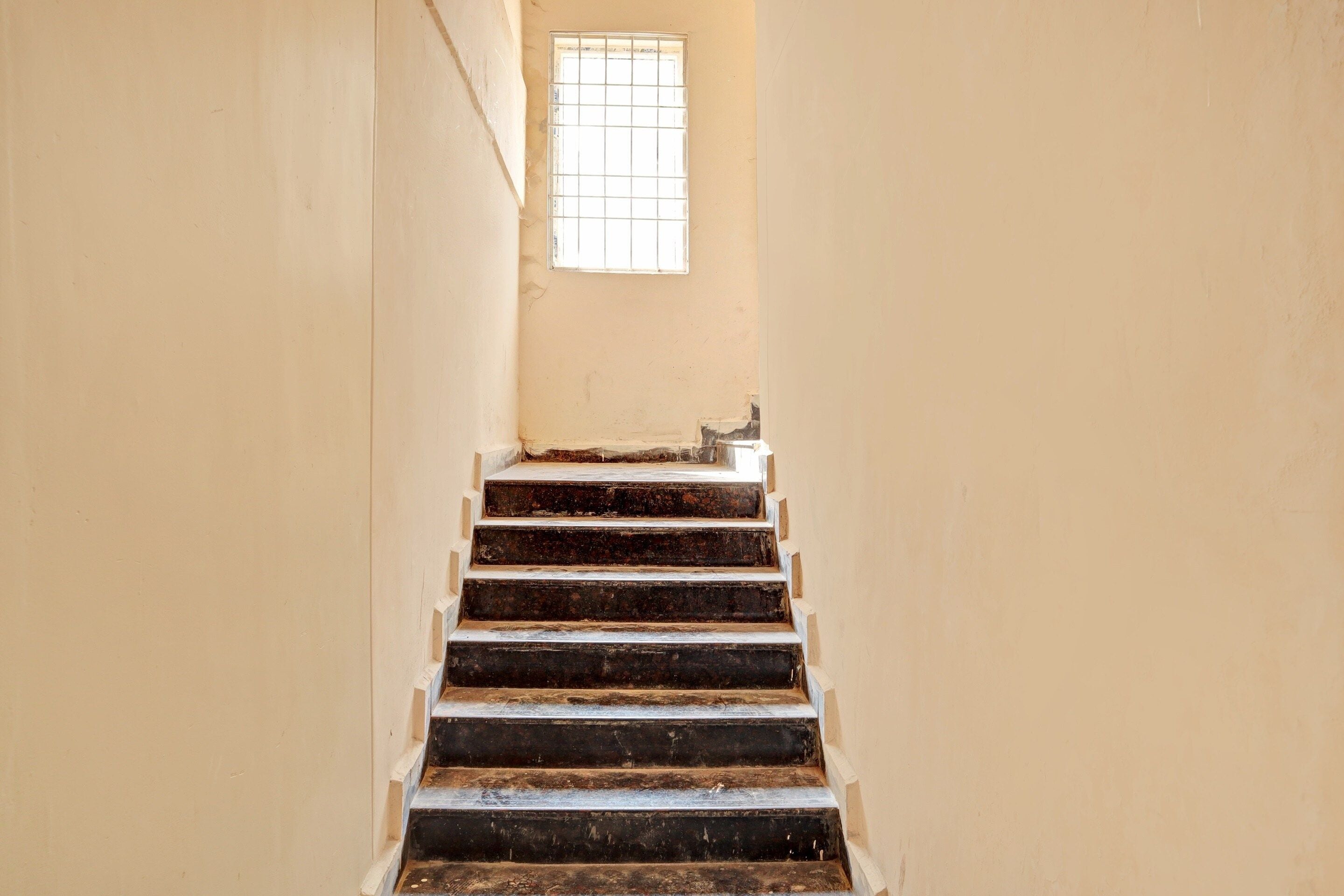 A narrow stairway with a window at the top.