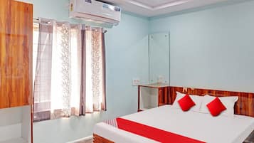 Una habitación de hotel con cama, espejo, unidad de aire acondicionado y cortinas.