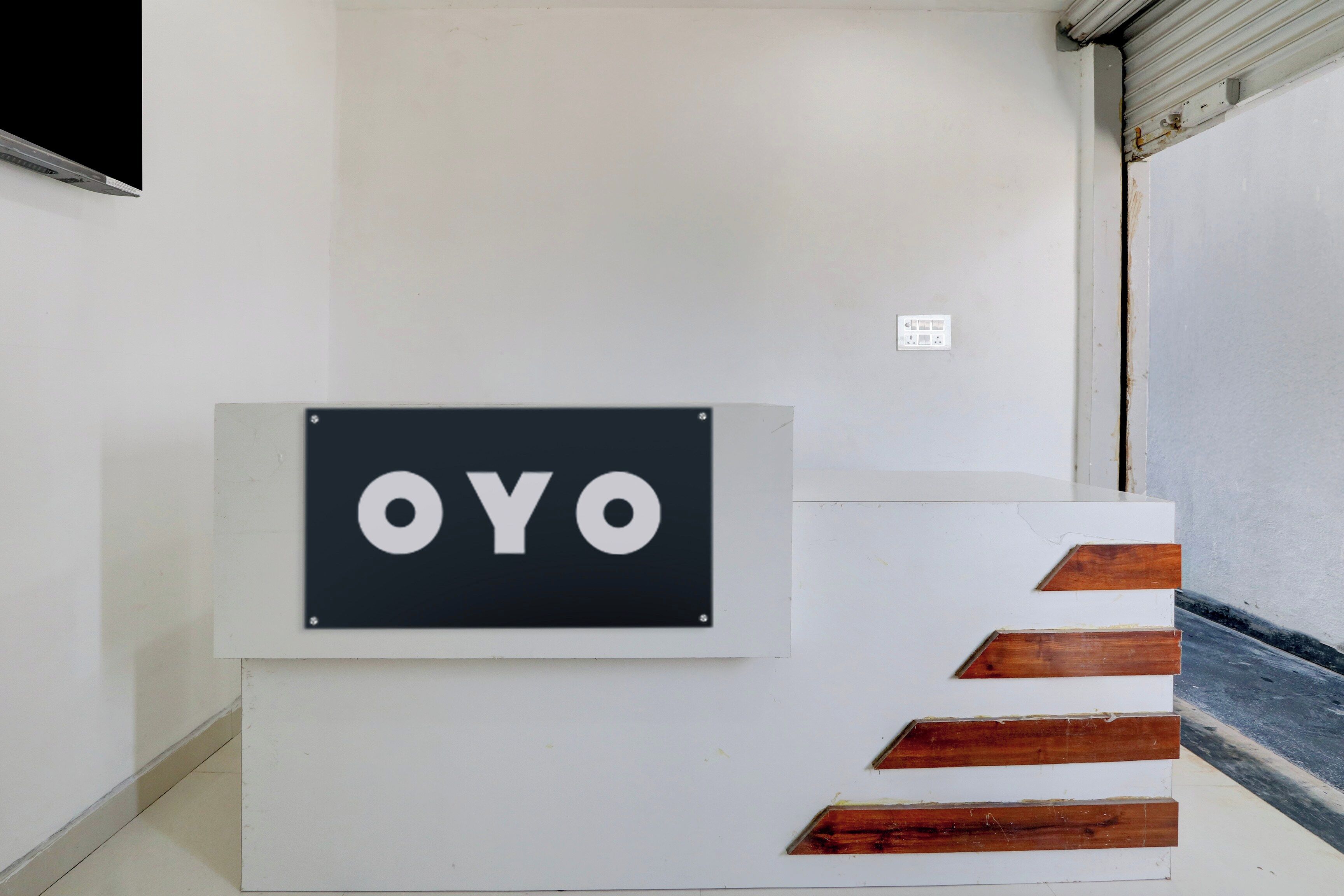 Ein Empfangsschalter mit einem Schild, auf dem 'OYO' steht, und eine Treppe mit Holzbodenstufen.