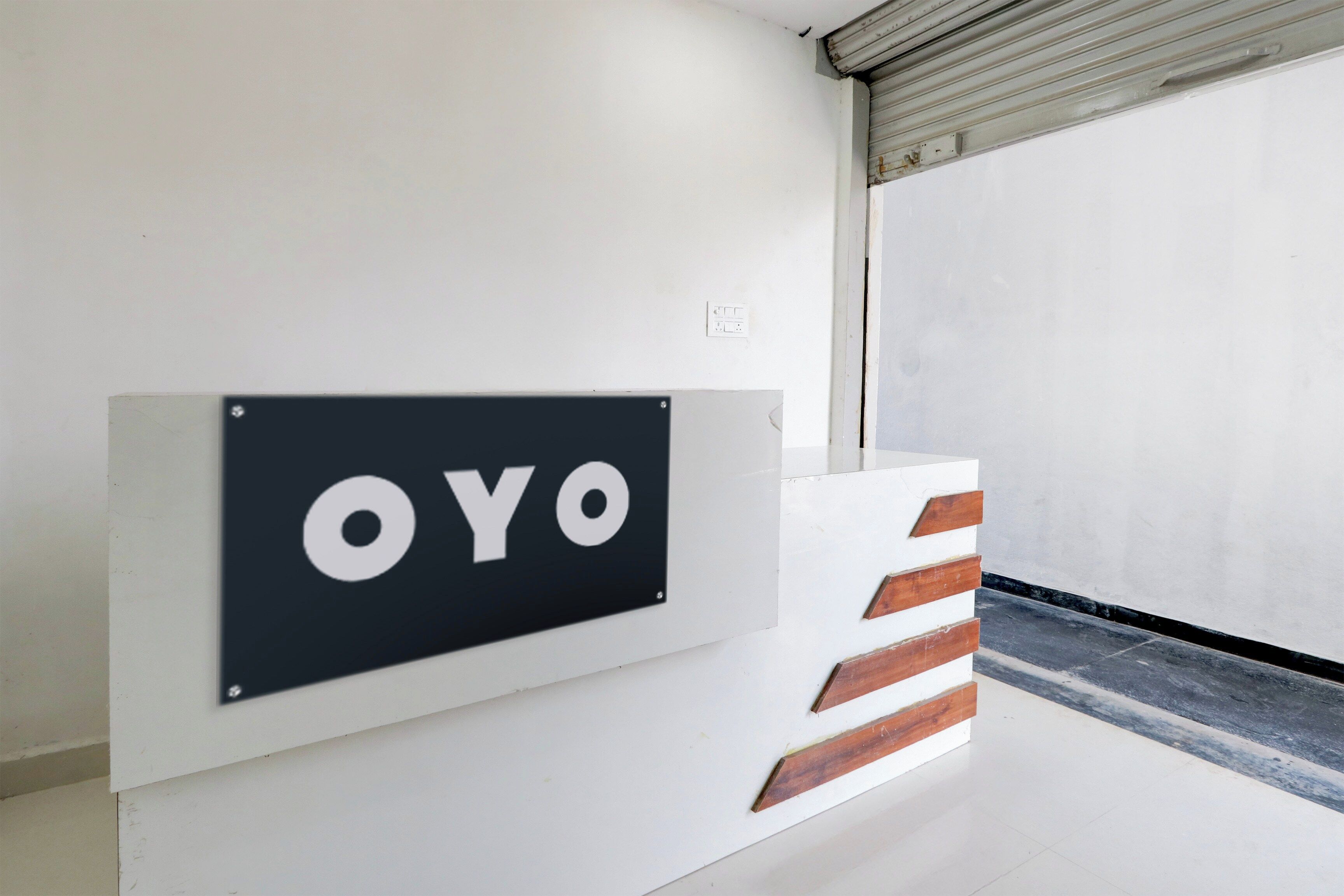 Un letrero con la palabra 'OYO' sobre una pared blanca, junto a un pilar blanco con detalles de madera.