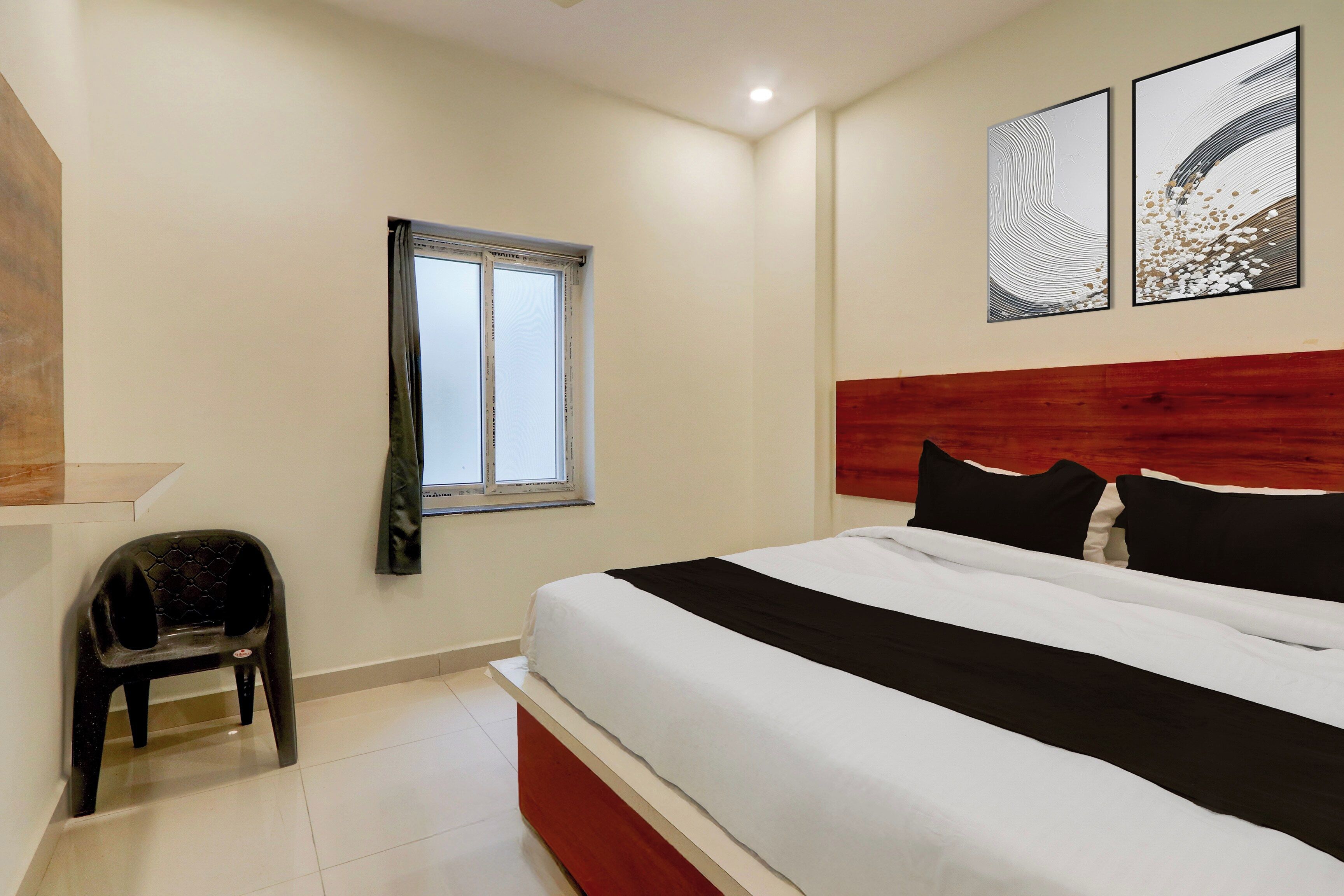 A bedroom with a bed, a window, a chair, and two wall-mounted artworks.