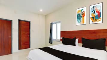 Habitación de hotel con una cama grande, dos puertas, una ventana con cortinas y dos obras de arte colgadas en la pared.