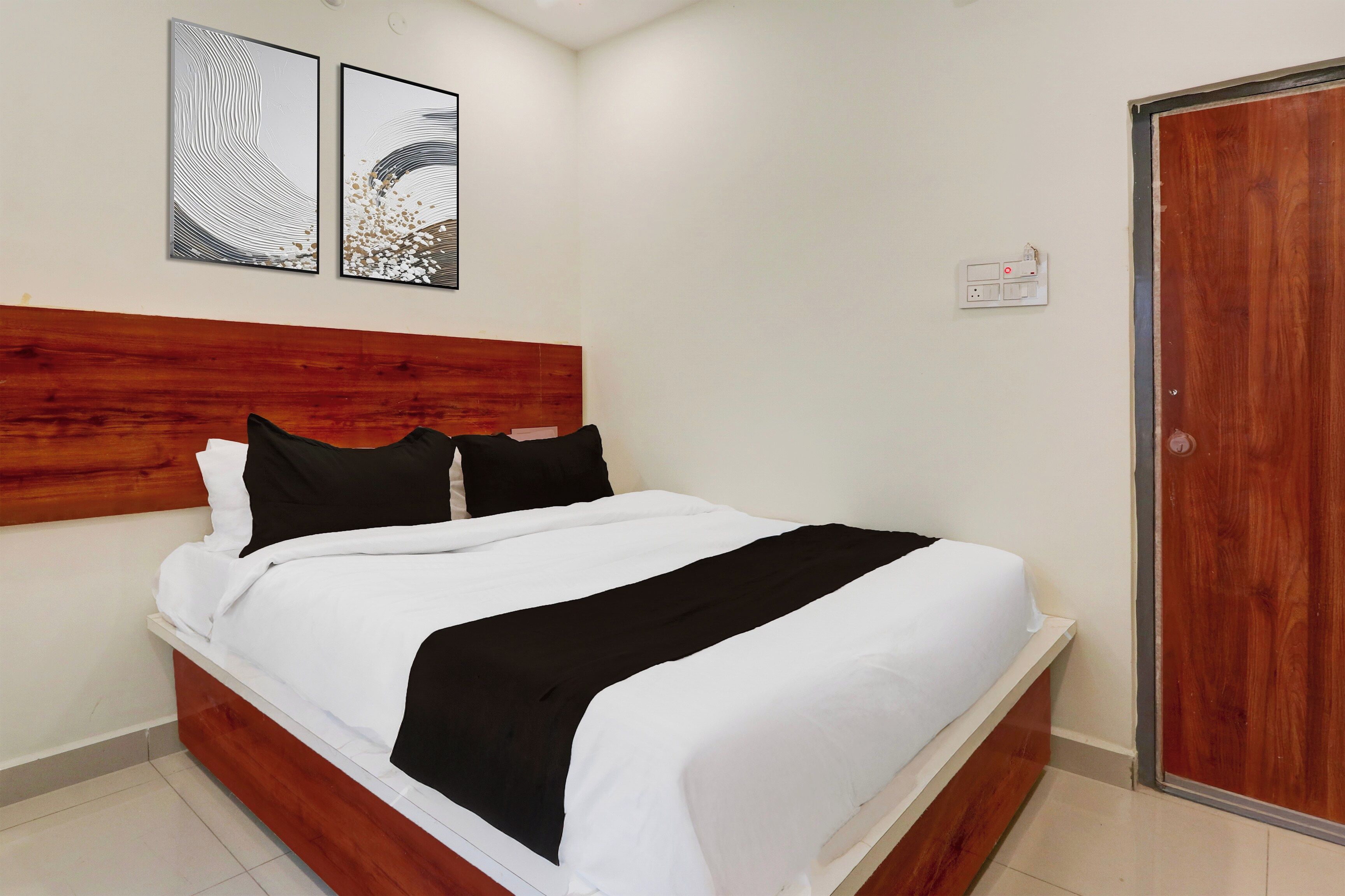 A neatly made bed with a wooden headboard, a white and black bedspread, and two pillows.