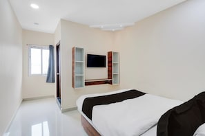 A modern bedroom with a bed, a TV mounted on the wall, and a window with curtains.