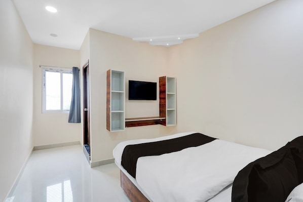 A modern bedroom with a bed, a TV mounted on the wall, and a window with curtains. - Hotel O RB Delight (Karīmnagar)