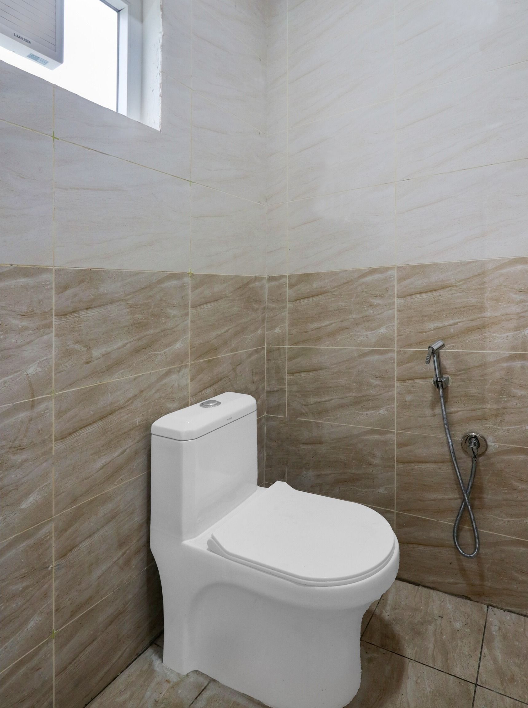 Ein Badezimmer mit Toilette, Dusche und gefliesten Wänden.