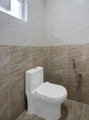A bathroom with a toilet, a shower, and tiled walls. - Hotel O RB Delight (Karīmnagar)