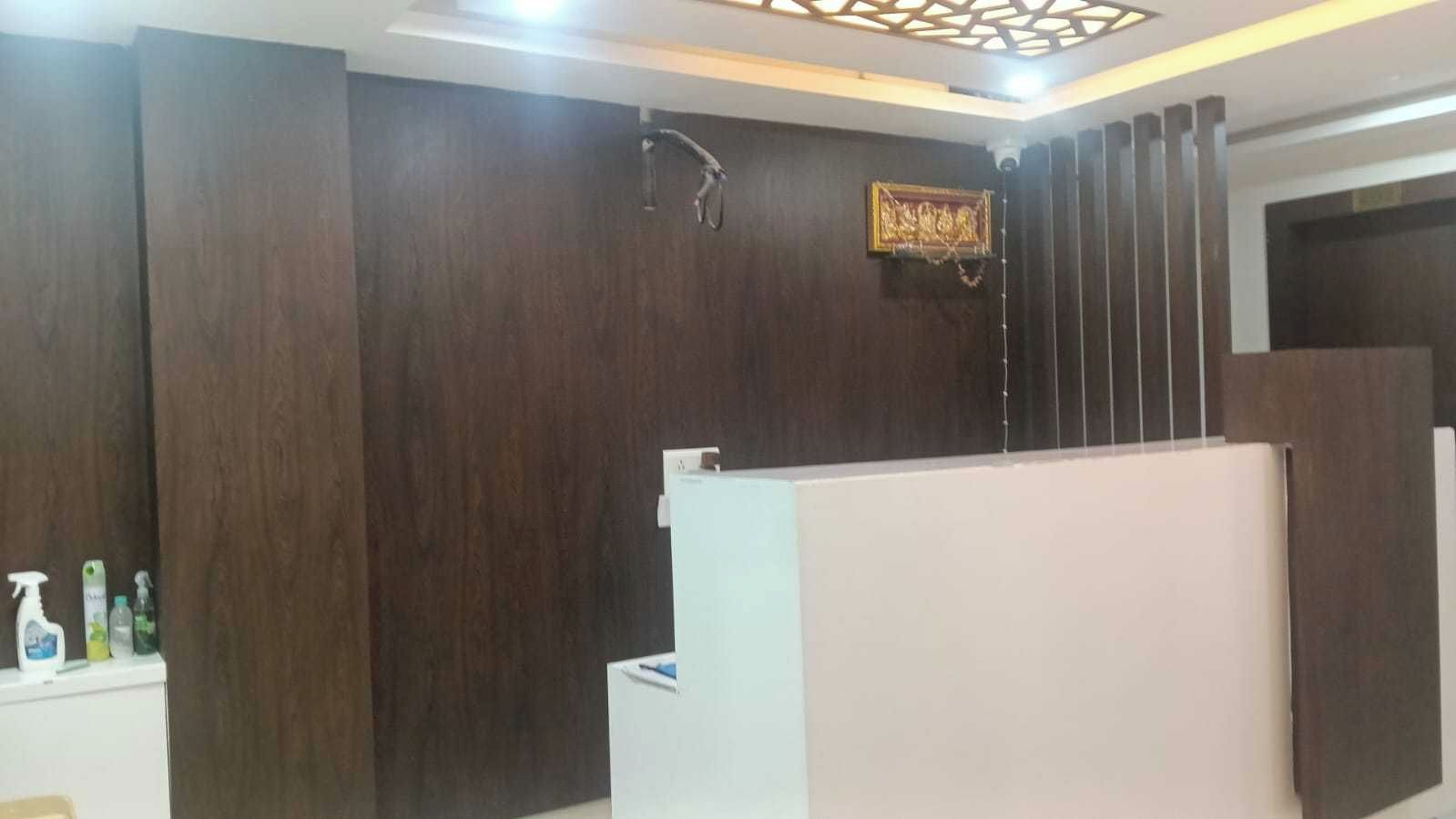 Un área de recepción con pared de paneles de madera, un mostrador de recepción y una lámpara en el techo.