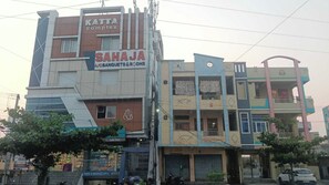 Un edificio de varios pisos con señalización que indica 'KATTA complex' y 'SAHAJA A/C BANQUETS & ROOMS'.