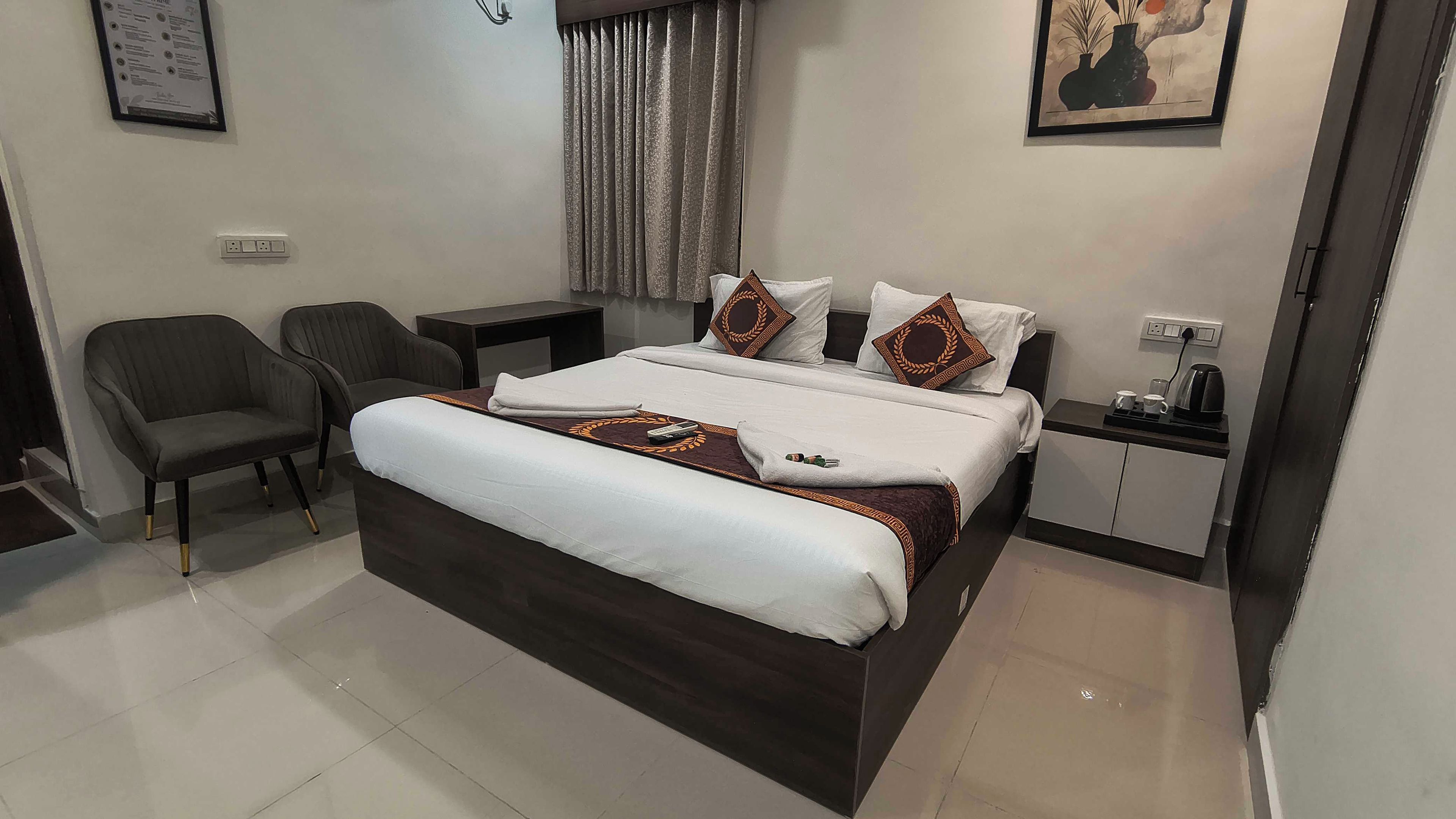 Una habitación de hotel con una cama, una silla, una mesita de noche y un cuadro en la pared.